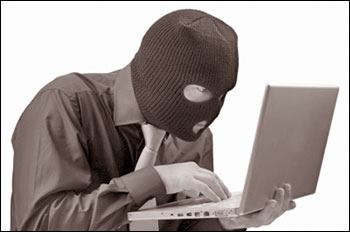 man wearing a ski mask looking at a laptop